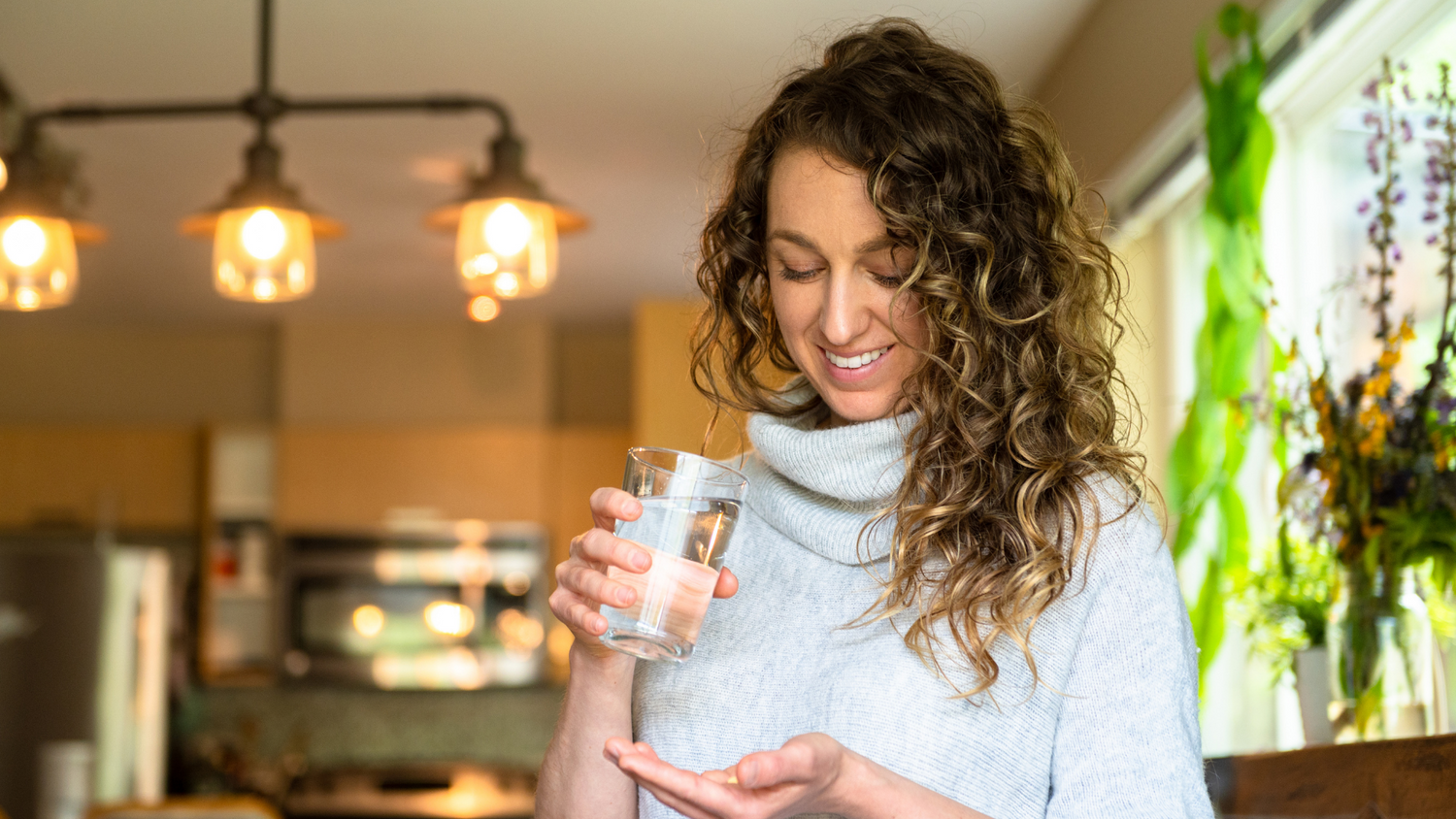 Woman holding water and supplement, considering how many supplements is too much