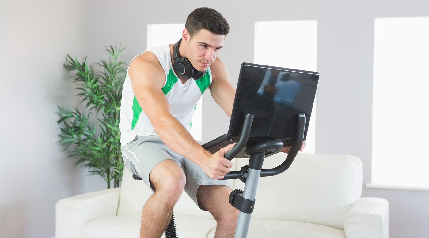  man on exercise bike working on laptop