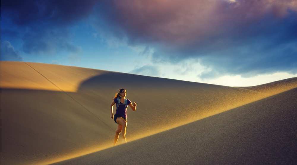 Woman running in sand dunes