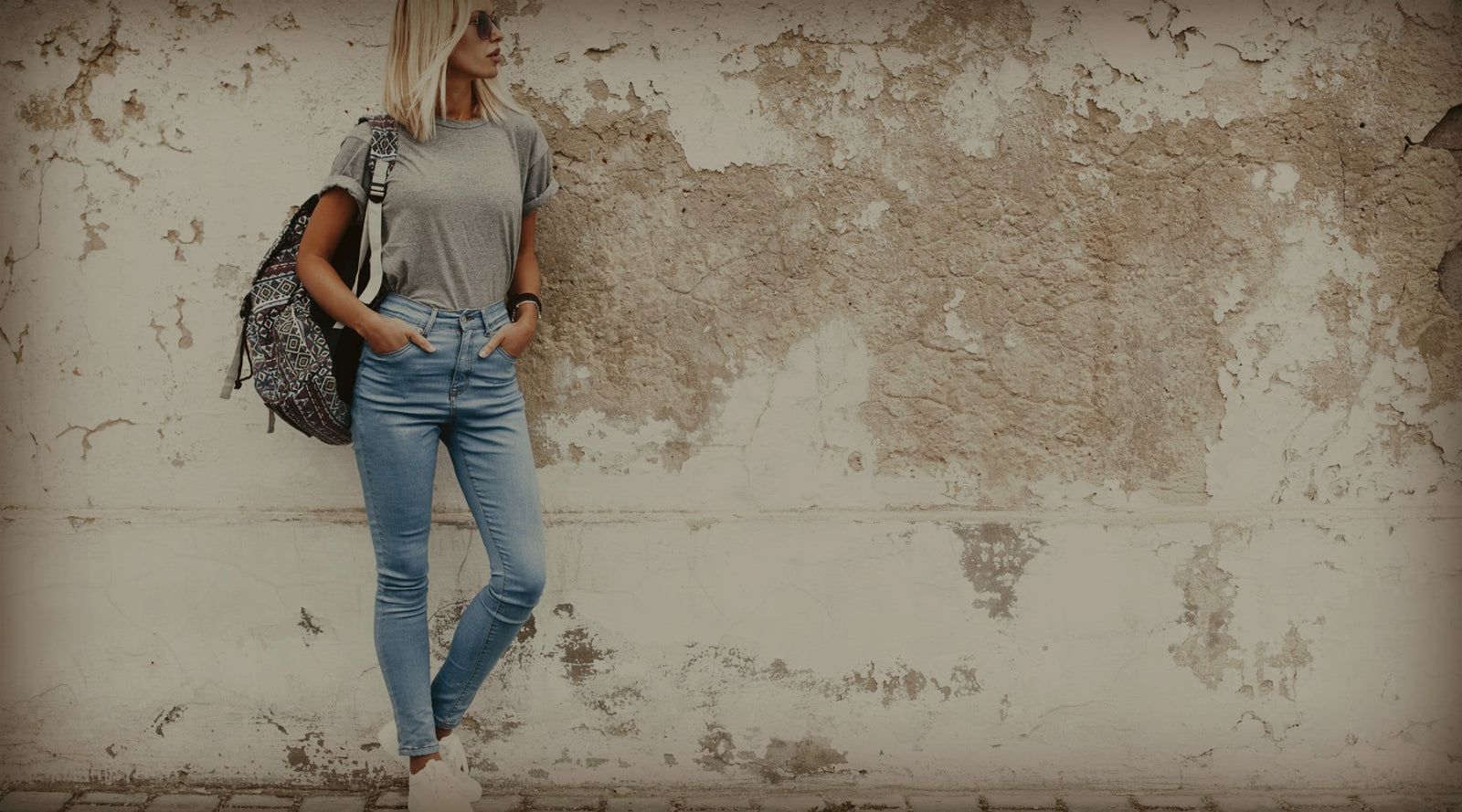  Woman in jeans leaning on a wall