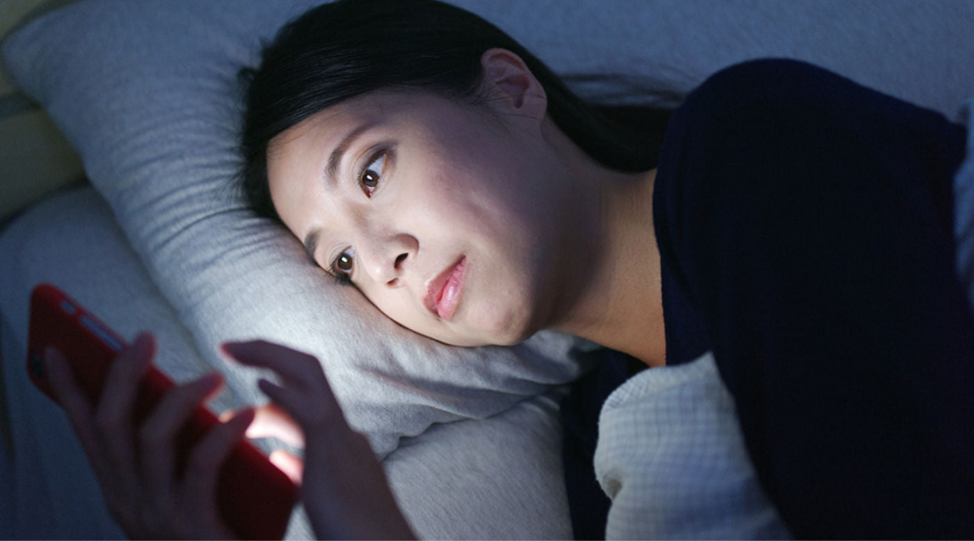  woman looking at phone in bed