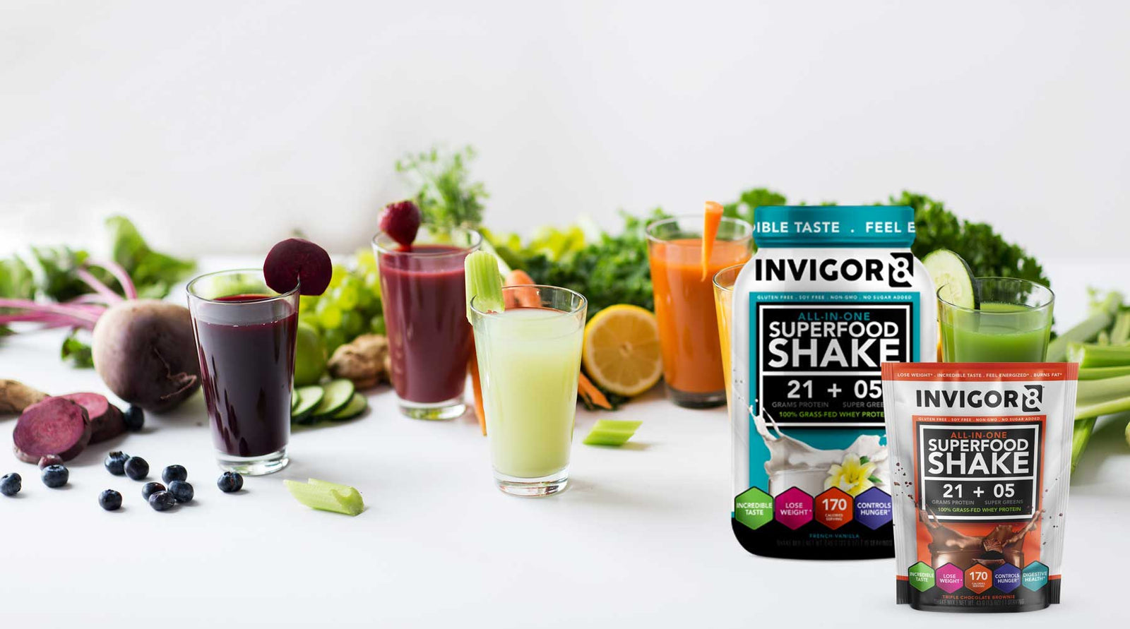  Invigor8 superfood shake bottle next to glasses of juice and vegetables 